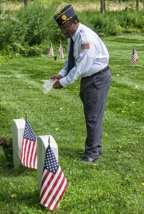 Father Ben Williams of Newton Post 86, spreads ashes on the graves of veterans.