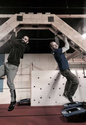 Chris Rivera (left) will head up the weightlifting/powerlifting component of Skyland's Ninja Warrior while facility owner Chris Ennis (right) will be in charge of the Ninja warrior training. Here the men dangle from one of the obstacles at the training facility built by Ennis. Photos by Laurie Gordon