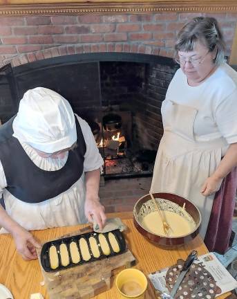 Open hearth cooking Una Leere prepares Corn Styx and Jane pours the batter to place in the Beehive Oven.