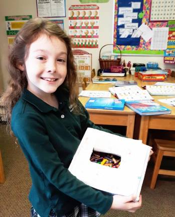 Roots and Shoots member, Anna Fraser, proudly displays the broken crayons she collected this week from her dance studio.