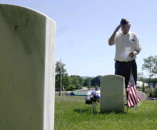 Raymond J. Doyle, American Legion Post 86, salutes and distributes the flag ashes on the grave of a fallen comrade