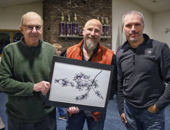 Judges Paul Michael Kane, Eduard Moldoveanu, and Jordan Basem hold the winning photo Dogwood by Joy Schmitz.