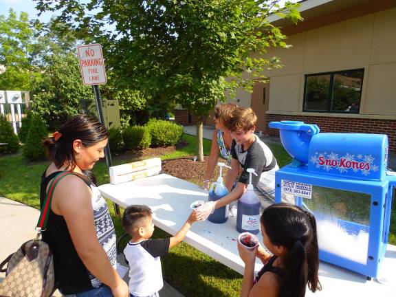 Back to School Fair preps families for September Entrepreneurial Jake Yaskovic hands customer Karina Cinto a snow cone at Project Self-Sufficiency's 30th Annual Back to School Fair