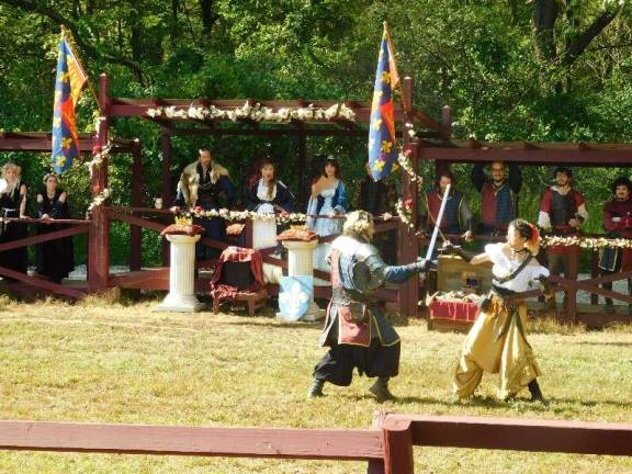 King James, Queen Misha, and their royal court look on while challengers engage in swordplay