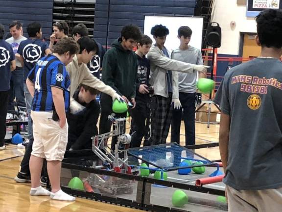 A student places a tri-ball on the robot.