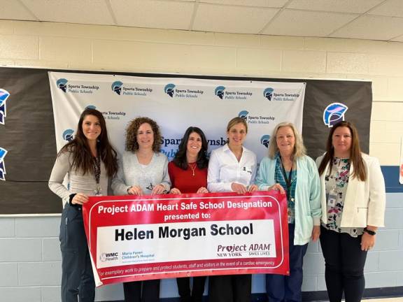 Holding a banner for Helen Morgan School in Sparta are, from left, school nurse Alexa Griffin; Alice Schoen, Dana Colasante and Dr. Christa Miliaresis of Project ADAM; school nurse Lillian Farrell; and Assistant Principal Tracy Rivera. (Photo provided)