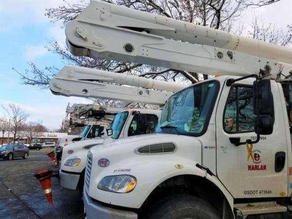 Utility trucks wait as workers take a break from round-the-clock shifts to restore power Thursday.