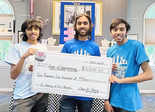 Iyer brothers Ayush, Akshat, and Aneesh present a check for the total amount raised during their Chess for Charity event in honor of Erin Beebe.