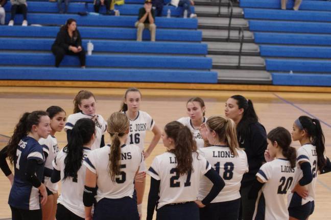 The Lions listen to their head coach Tyler Singh, third from right, during a timeout.