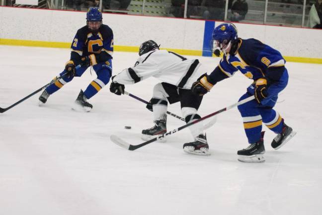 A Kinnelon/Jefferson/Sparta United hockey player maneuvers between two opponents.