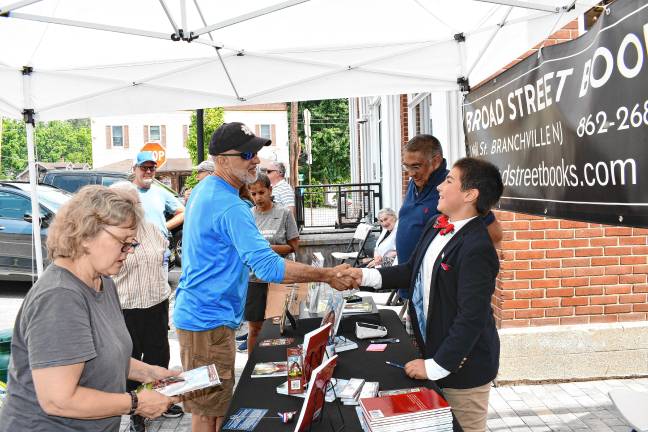 Young author’s book deals with big themes ZS2 Zy Saturnees, right, shakes hands with a fan.