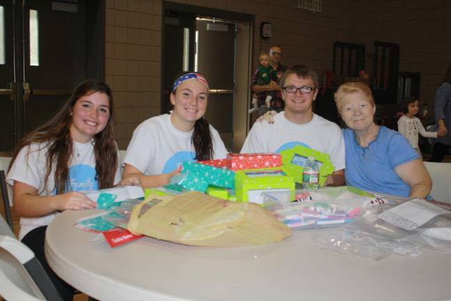 Pass it along holds Family Volunteer Day Alex Curran, Courtney McKenna, Daniel Baker and Colleen Russell assemble boxes for Christmas cookies.