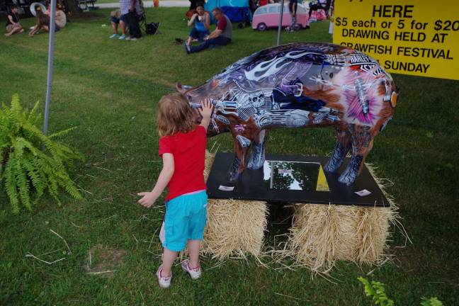 Crawfish fest goes 'down home' A young attendee pets a colorful fiberglass pig, creation of Art Frisbie of Wantage.