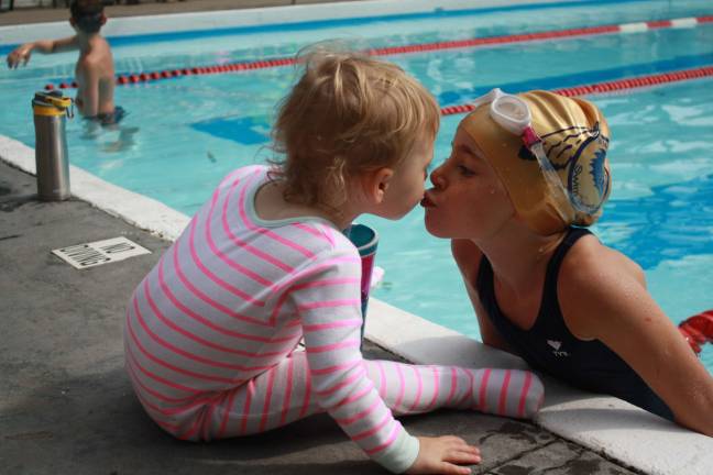Swimmer Ella Duphiney takes a break in between laps to kiss her sister, Tessa.