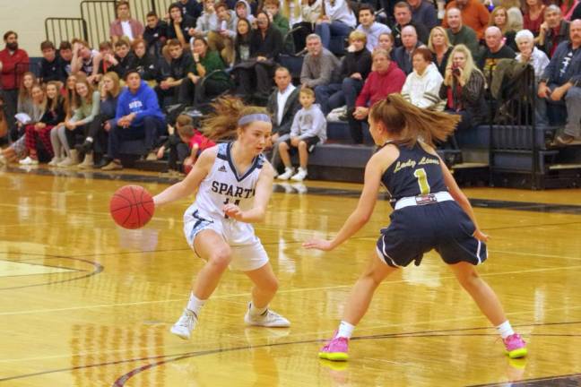 Spartan Ally Sweeney dribbles the ball while covered by Pope John's Carly Fitzmorris in the first quarter . Sweeney grabbed 4 rebounds and scored 19 points.