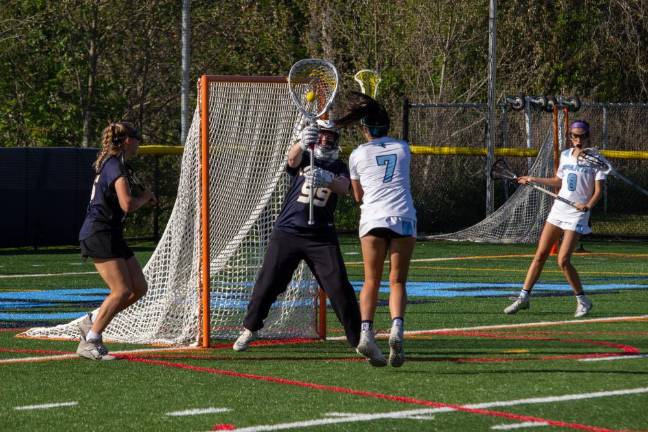 Vernon goaltender Abby Sokolewicz (99) defends an attempted goal by Spartan midfielder Uma Kowalski (7). Riley Lewicki of Vernon, left, and Brooke Weyant of Sparta, back right, support their teammates in the Vernon defense zone.