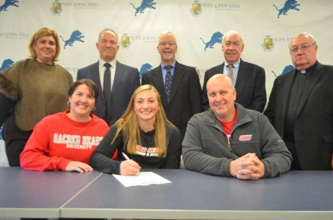 Kelly Peter signs her National Letter of Intent for swimming at Sacred Heart University. Seated next to Peter are her parents, Kim and Donald. Back row: Athletic Director Mia Gavan, Principal Gene Emering, Pope John swimming head coach Thomas Kane, former Pope John swimming head coach Ed Wynne, and Pope John President Rev. Msgr. Kieran McHugh.