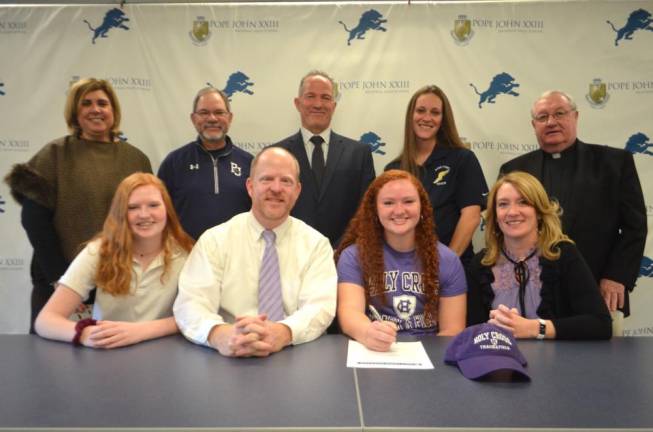 Maura Campbell signs her National Letter of Intent for track and field at Holy Cross. Seated next to Campbell her parents, Seamus and MaryAlice, and her sister, Jane. Back row: Athletic Director Mia Gavan, assistant track and field coach Tom Morro, Principal Gene Emering, assistant track and field coach Ashley DiGidio, and Pope John President Rev. Msgr. Kieran McHugh.
