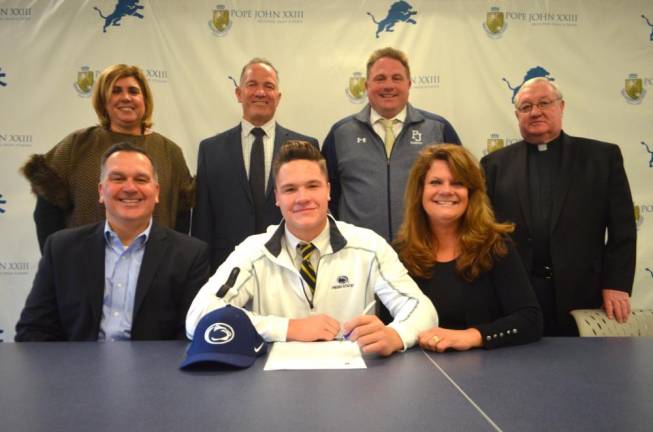 Luke Chenault signs his National Letter of Intent for baseball at Penn State University. Seated next to Chenault are his parents, Jack and Kimberley. Back row: Athletic Director Mia Gavan, Principal Gene Emering, head coach Vin Bello, and Pope John President Rev. Msgr. Kieran McHugh.