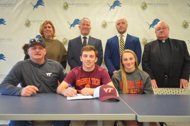 Eddie Ventresca signs his National Letter of Intent to continue his academic and wrestling careers at Virginia Tech. Seated next to Ventresca from left, are his father, Ed, and his sister, Gianna. Back row:Athletic Director Mia Gavan, Pope John Principal Gene Emering, Pope John wrestling head coach Austin Alpaugh, and Pope John President Rev. Msgr. Kieran McHugh.