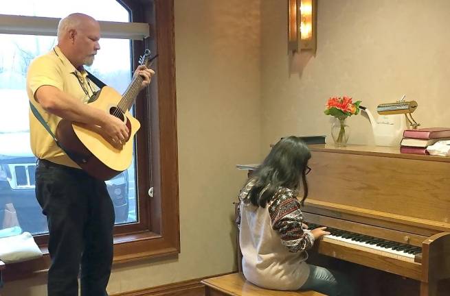 WVRHS student Tamara plays piano as staff member Dave plays guitar during a visit in 2019 (Photo provided)