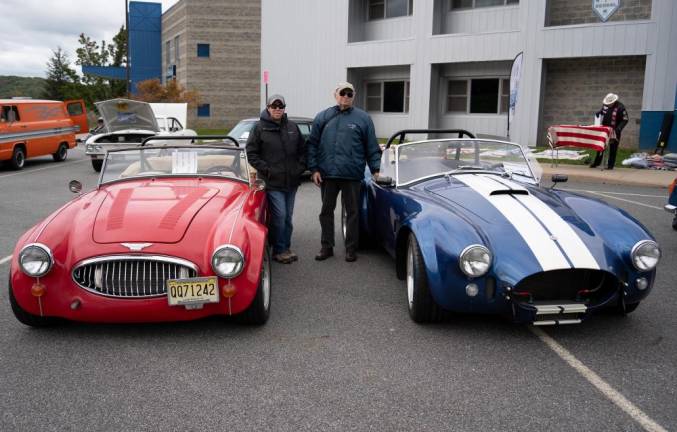 Sandy and Jen Smith stand by Sandy’s red Austen Healey and blue Cobra.