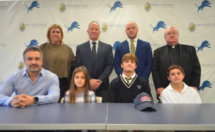 Kaya Sement announces his commitment to continue his academic and wrestling careers at the University of Pennsylvania. Seated next to Sement, from left, are his father, Eralp, his sister, Kayra, and his brother, Eren. Back row:Athletic Director Mia Gavan, Pope John Principal Gene Emering, Pope John wrestling head coach Austin Alpaugh, and Pope John President Rev. Msgr. Kieran McHugh.