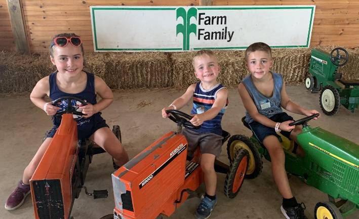 Cami, Chase and Logan Morrow have a great time as their grandmother and parents watch them ride min tractors in the Familyl Fun section of the State Fair on Sunday, Aug. 4.