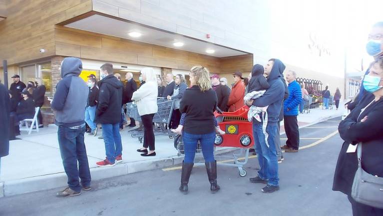 Shoppers held children and listened to music. One shopper said he wanted to find out which door to enter to find the item he needed. (Photo by Frances Ruth Harris)