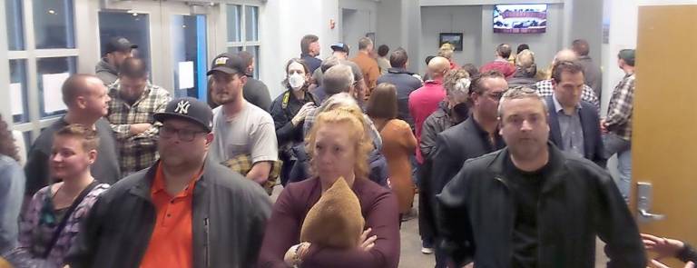 Members of the public who were squeezed out of the main meeting hall watched the hearing on television sets in the vestibule (Photo by Frances Ruth Harris)