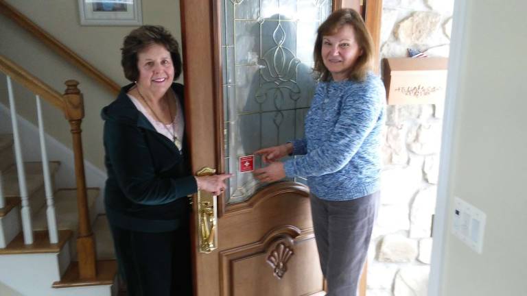 Vial of Life Chair Marjorie Strohsahl, left, and SWC President Roberta Dyrsten affix alert decal on door Photos provided