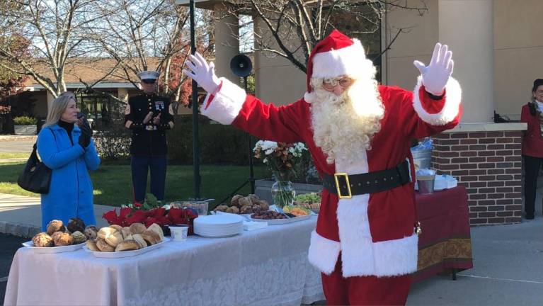 Santa greets the crowd. At left is Christine Norbut Beyer, commissioner of the state Department of Children &amp; Families.