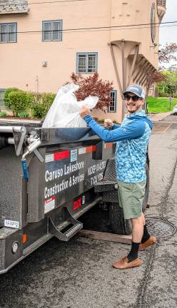 Danny Caruso adds a bag of trash to the container. He provided the trailer to take away the trash.
