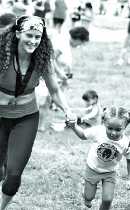 Carmen Caruana of Long Beach, NY, runs with her four-year-old daughter Juanita Florendo in the Kids Spartan Race. Caruana completed The Spartan Race earlier in the day.