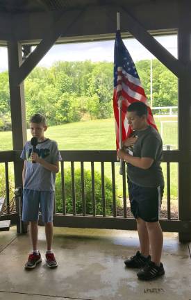 Collin Webb singing and Aiden Bellow holding the flag. Both are 6th graders at The Stillwater School and participants in The Bears Youth Running Program.