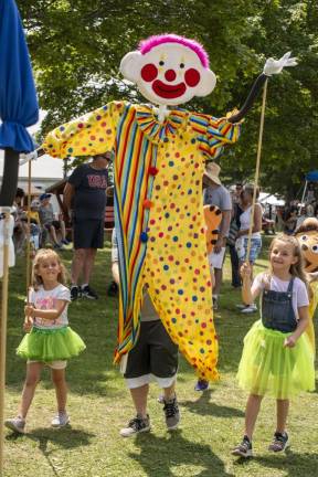 Addie Pakestein, 7, of Vernon and her sister Leah, 9, march with a giant clown puppet, with help from their father, Eric (you can see his feet), during the Amazing Anastasinis' ‘Join the Circus’ show. (Photo by John Hester)