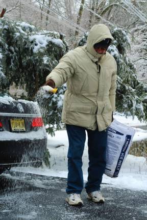 Jim Sodt, of Lake Mohawk, coats his driveway with Ice Melt after a morning of shoveling.  "Well, thirty years of winter storms here in this house, why not another?" he said, laughing. (Photo by Shannon Kuratli). 