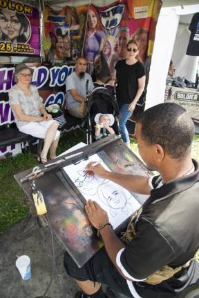 FR24 Caricaturist Tier Gaither of Decatur, Ga., draws, from left, Lubby Mumoli, Joseph and Rosalyn Velez, and their daughter, Rosella, 8 months, all of Little Falls. (Photo by John Hester)