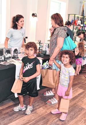 Emliia Paradisi Garces and Isabel Paradis hold their mother's hand.