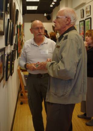 At left, photographer Keith Utter of Hainesville talks about his photos with fellow photographer Ernest Duck of Hamburg. At right is Mr. Duck&#xfe;&#xc4;&#xf4;s wife Renate.