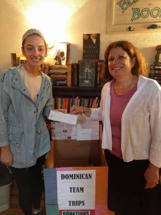 Erin Louglas, proprietor of the cafe Between the Bread in Newton, presents Mary Rapuano with a $200 check in support of Dominican Team Trips LLC. Louglas had pledged a portion of her receipts during the October 13-14 weekend to Dominican Team Trips, which conducts a humanitarian excursion to the Dominican Republic each autumn. (Photo submitted).