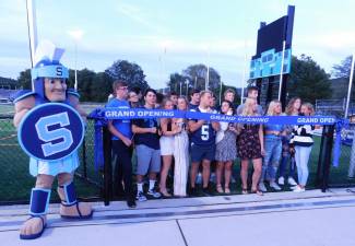 Sparta High School athletes, the marching band, and the Spartan mascot prepare to cut the ribbon on their new turf field, on Monday, Aug. 26, 2019.