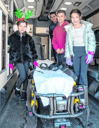Charlotte, Connor and Elizabeth McCrossen with Ryan Grycuk examine an ambulance.