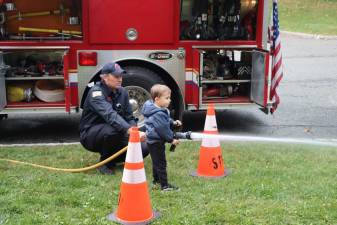 SF1 Firefighter Joe Yanko helps Sammy Papa control the fire hose at the Sparta Township Fire Department’s second annual open house. (Photos by Dave Smith)