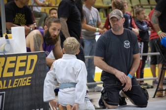 Coaches Frank Wallace (left) and Moe Johnson (right) speak with Josh Enberg before his match