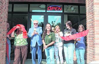 Greene’s Beans Cafe owner Kelsey Walter, center, cuts the ribbon.