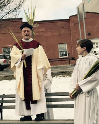 Father Robert Griner starts the Palm Sunday service on the Green in Newton. His son serves as an accolyte Photos by Laurie Gordon