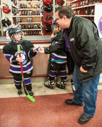 Brad Meyers, founder of the Monarchs, hands a hockey puck to team member Alex Anson