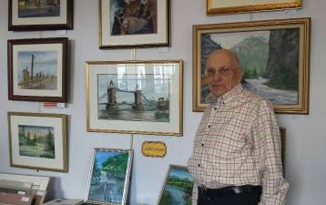 Herb Stanske of Sparta with a wall of his paintings.