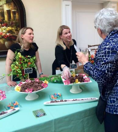 The Koza sisters (from left, Jennifer and Stephanie), owners of the Chocolate Goat, talk to a guest at a Project Self-Sufficiency fundraiser. Photo by Laurie Gordon